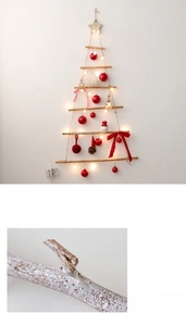 Detail of handcrafted wooden wall Christmas tree with LED lights and festive red ornaments