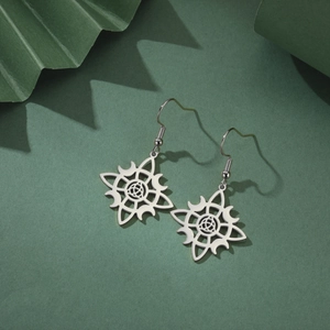 Macro view of silver stainless steel moon earrings with intricate cutout witch knot