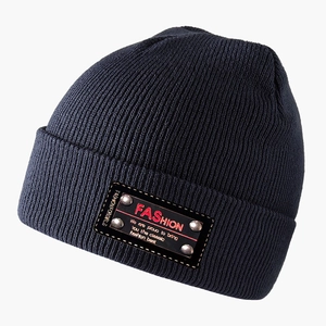 Detail of navy knit beanie showing ribbed texture and leather patch with metal rivets