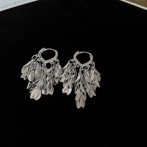 Detail of silver tassel earrings with leaf-shaped metal scales on a black velvet background