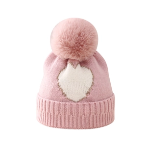 Pink baby knitted beanie with white heart pattern and soft faux fur pompom details