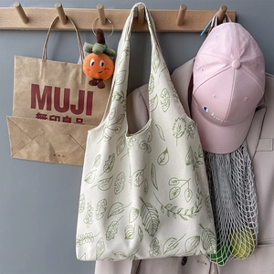 Close-up of canvas tote bag with green leaf patterns hanging on a wooden hook