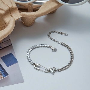 Detail of stainless steel bracelet featuring zircon tennis chain and heart charm detail