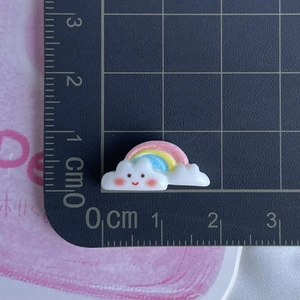 Close-up of small rainbow cloud resin accessory with ruler showing 2cm width scale