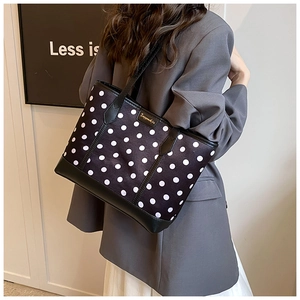 Polka dot tote bag with black leather straps shown on model for size perspective