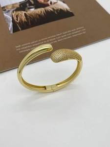 Macro shot of gold plated open cuff bracelet with cubic zirconia paving and polished finish