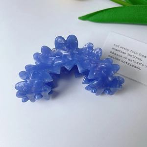 Blue marble acetate hair claw clip with wavy cloud edges on a minimalist background