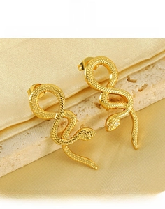 Detail of gold snake earrings featuring intricate scale textures on a luxury satin background