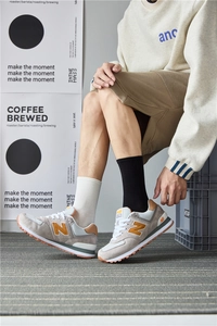 On-foot shot of retro 574 jogging shoes in grey with orange accents and gum sole