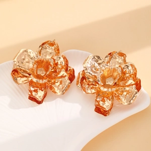 Macro detail of gold-tone flower earrings with irregular hammered texture on shell plate