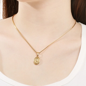 Collier pendentif religieux ovale vintage en acier titane doré sur un mannequin