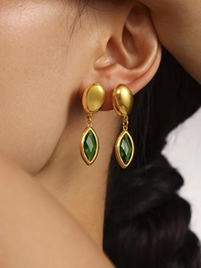 Détail de boucles d'oreilles dorées 18 carats avec verre en cristal vert taillé marquise