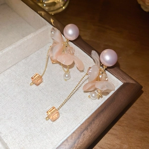 Dettaglio orecchini a fiore rosa con lunghe nappe metalliche e dettagli di perle