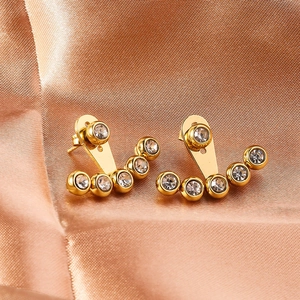 Macro view of gold detachable stud earrings with five sparkling crystals on champagne silk