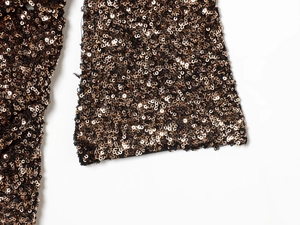 Macro shot of dense bronze sequins on black mesh fabric showing detailed craftsmanship