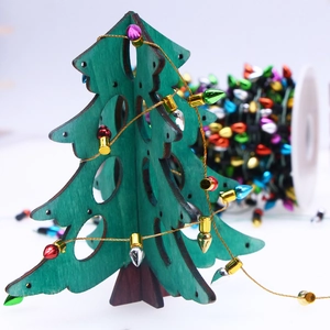Macro detail of a green wooden Christmas tree with colorful metallic bulb light strings