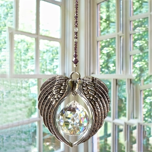Detail of faceted crystal ball with silver angel wings hanger and purple beads decoration