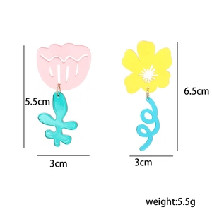 Detail view of asymmetric floral earrings with pink tulip and yellow flower charms