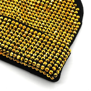 Gros plan du bonnet punk en acrylique noir orné de strass dorés scintillants et denses