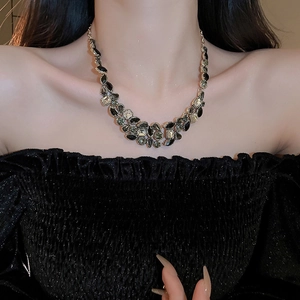 Detail of luxury teardrop tassel necklace with dark gemstones and gold metal finish