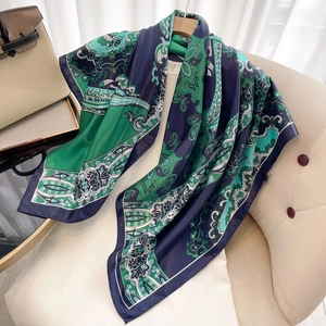 Detailed view of a blue and green paisley silk-like scarf draped over a quilted chair