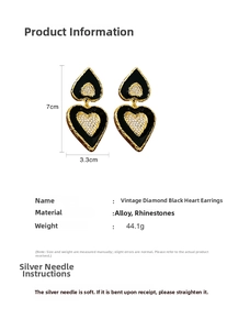 Detailed view of vintage heart-shaped earrings with black enamel and sparkling rhinestones