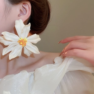 Detail of white acrylic flower earring with yellow stamen worn by model