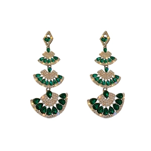 Luxurious fan-shaped gold earrings with sparkling diamonds and green emerald gemstones