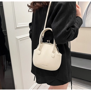 Detail of a beige vintage shell bag with metal clasp and fashion logo text on PU leather