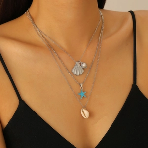 Dettaglio di una collana a strati oceanica con pendenti a conchiglia e stella marina su modella