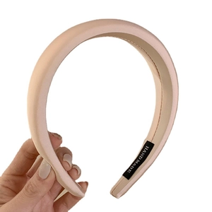 Handheld light pink wide satin headband with handmade label for elegant hair styling