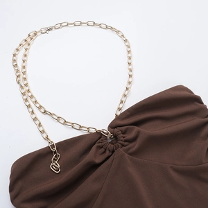 Detail of sexy brown mini dress featuring gold chain straps and pleated neckline