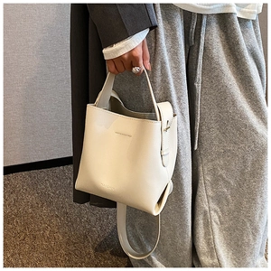 Close-up of cream white bucket bag featuring elegant leather texture and branded embossing