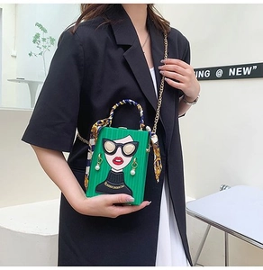 Detail of green graffiti box bag featuring cartoon face with 3D pearl earrings and silk scarf