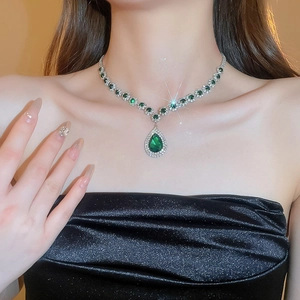 Detail showing pear-shaped green pendant with emerald-cut gems and crystals necklace