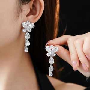 Detail showing long silver flower earrings with sparkling water drop zircon pendants on model
