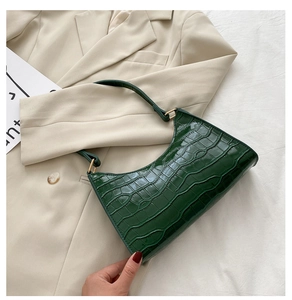 Close-up of dark green faux crocodile leather texture and golden metal buckle details