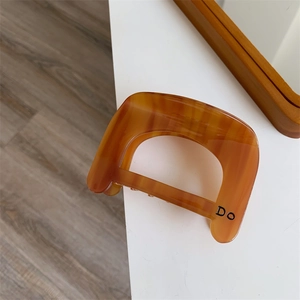 Detail of amber tortoiseshell acetate hair claw clip with black Do letter print