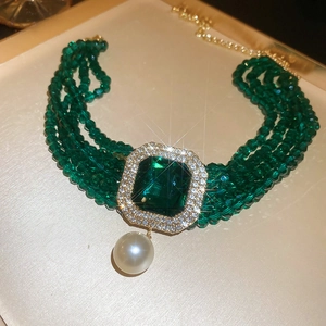 Close-up of vintage multi-layer green bead choker with square emerald and pearl drop