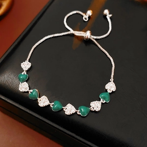 Detail of silver heart bracelet with green gemstones and adjustable chain on leather
