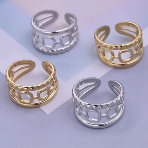 Close-up of hollow geometric rings in gold and silver showing intricate layered metal textures