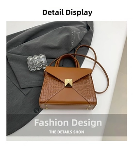 Detail view of brown faux crocodile texture handbag with gold pyramid stud and strap