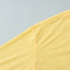 Detail of bright yellow knitted fabric showing breathable texture and double-stitched seams