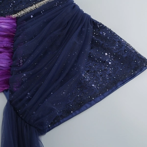 Détail d'une robe marine à paillettes avec plumes violettes et bordure en strass argentés