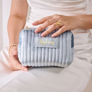 Detail of light blue velvet cosmetic bag with ribbed stitching and gold Sydney embroidery