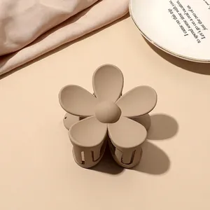 Detail of matte floral hair claw clip in beige on minimalist decorative ceramic plate