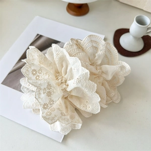 Détail de chouchous en dentelle beige avec broderie florale et bords festonnés
