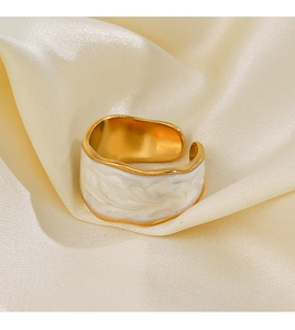 Dettaglio di un anello dorato a onde con smalto bianco su seta elegante