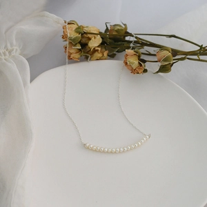 Elegant minimalist freshwater pearl necklace with silver chain on white ceramic tray