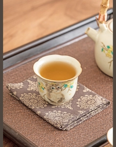 Detail of Ru Kiln ceramic teacup with cute cat and yellow flower patterns on dark cloth